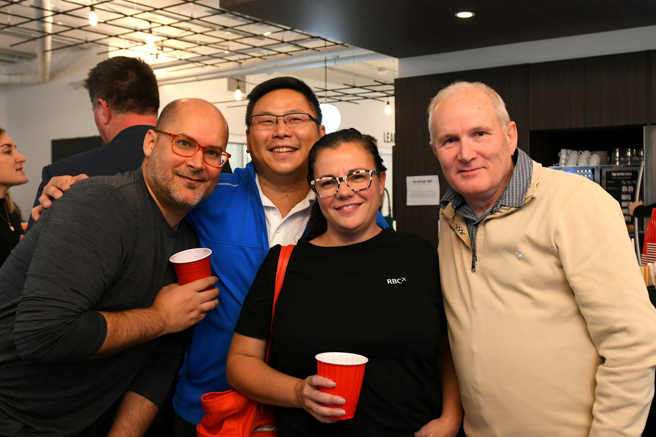 Group of four diverse people smiling and posing for a photo at a Startup TNT pitch night.